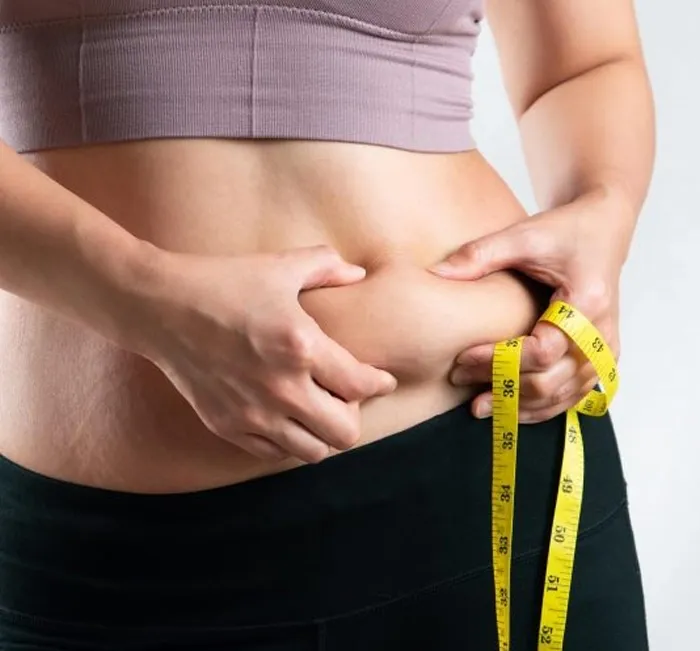 Woman measuring her waist with a tape measure